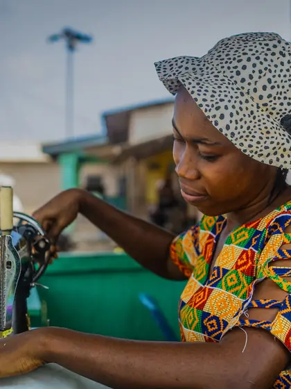 A woman sewing fabric at a machine in her workshop