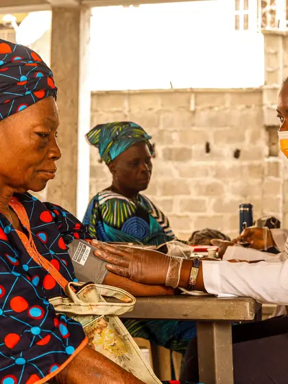 A health worker checking an elderly woman's blood pressure