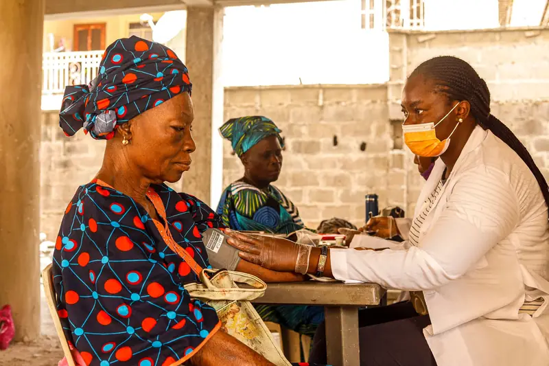 A health worker checking an elderly woman’s blood pressure