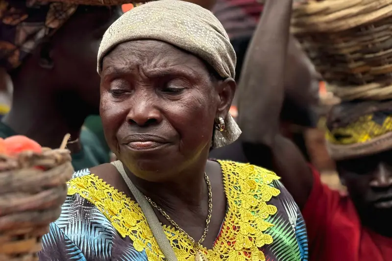 An elderly trader with baskets of fresh produce