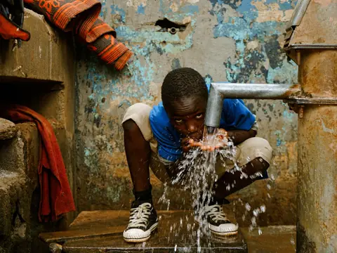 A boy drinking clean water from a tap